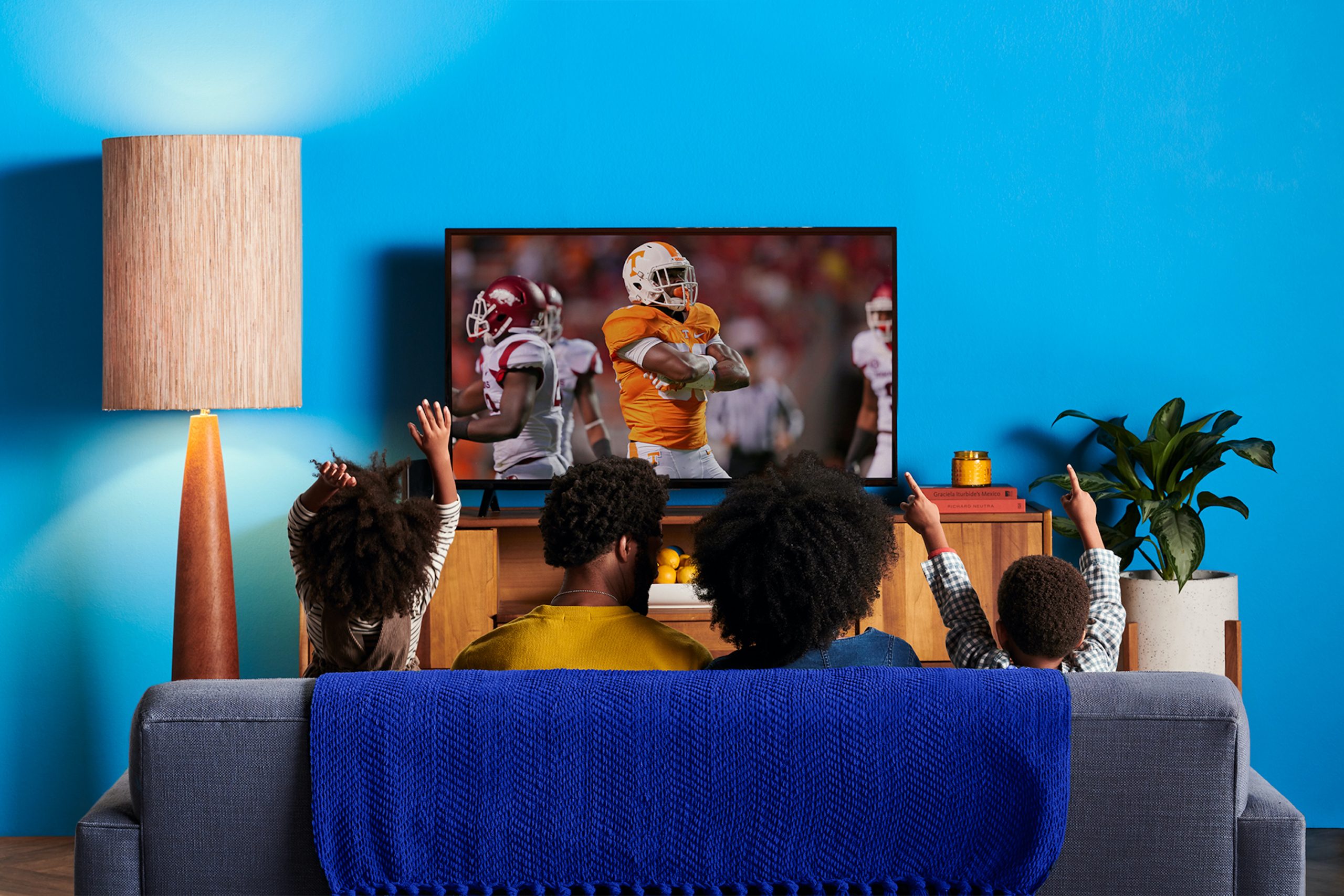 Family on the couch watching football on Sling TV