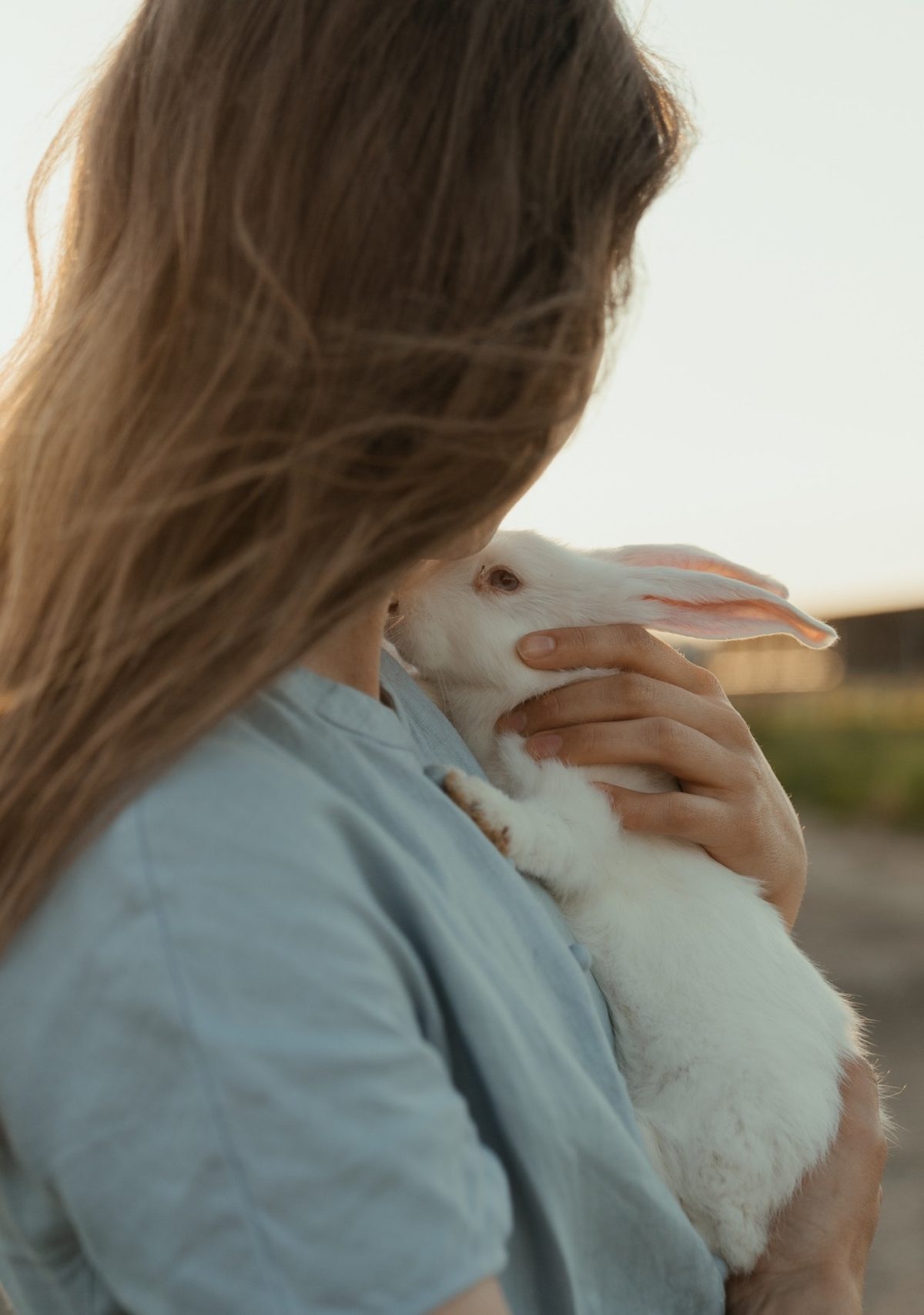 a girl with long hair holds a white rabbit to her chest