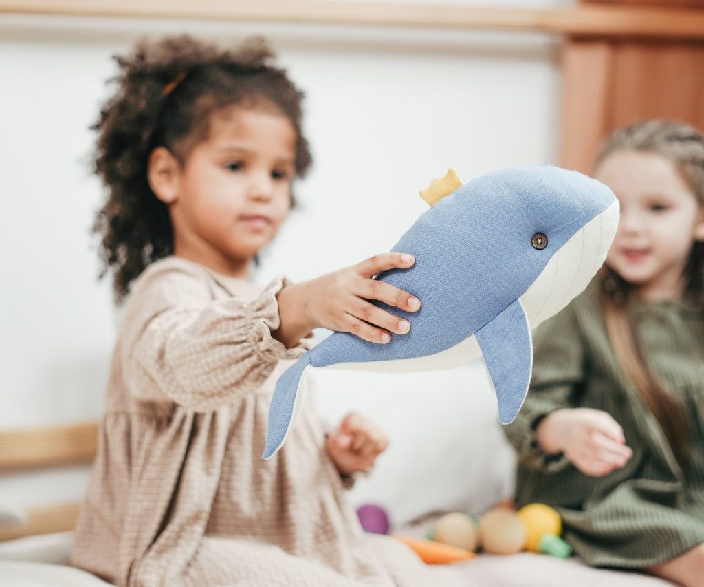 A little girl holding a stuffed blue whale.