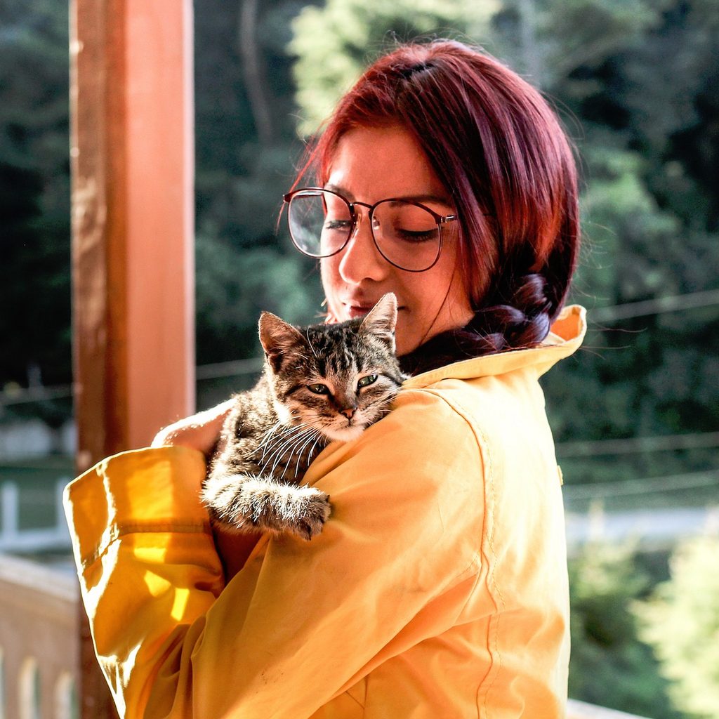 Woman holding a tiger cat against her shoulder