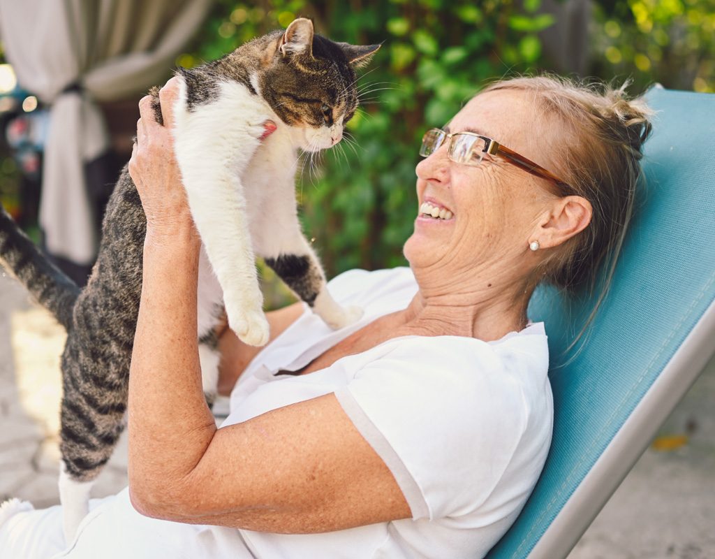 Older woman hugging cat.