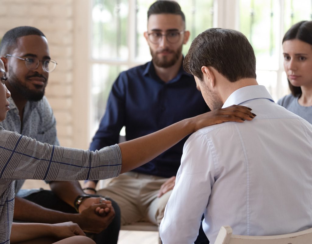 Support group members comforting a young man.