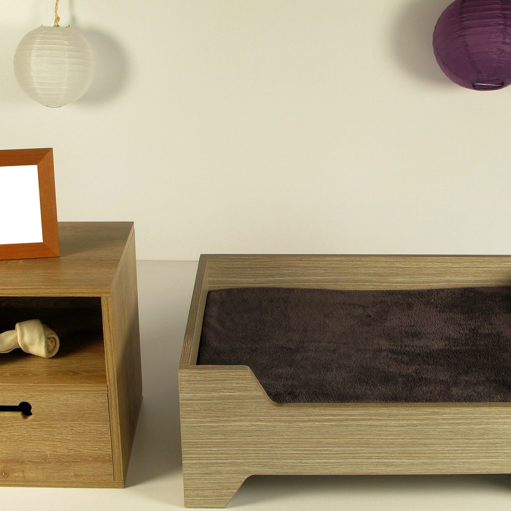 a wooden homemade dog bed next to a small wood side table