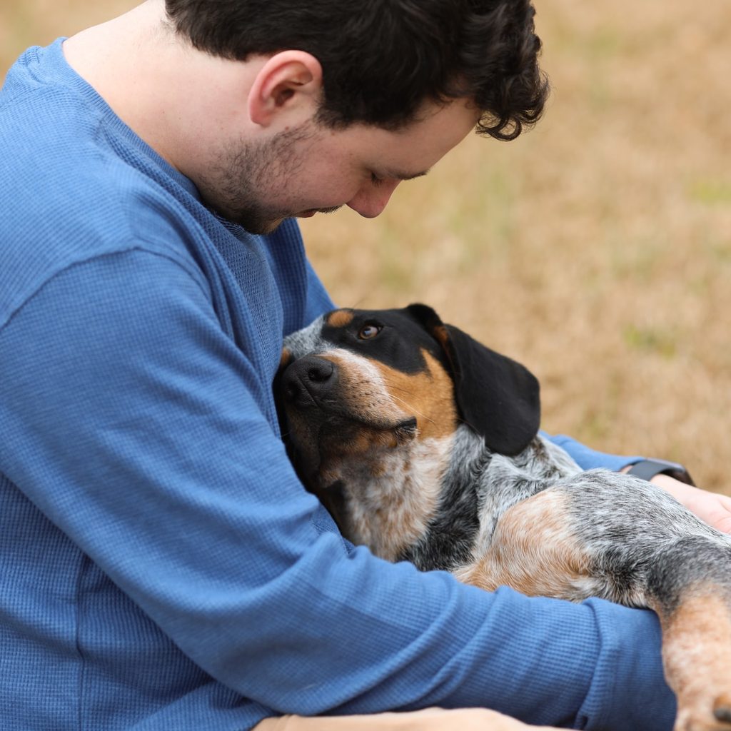 man in blue shirt with dog in lap