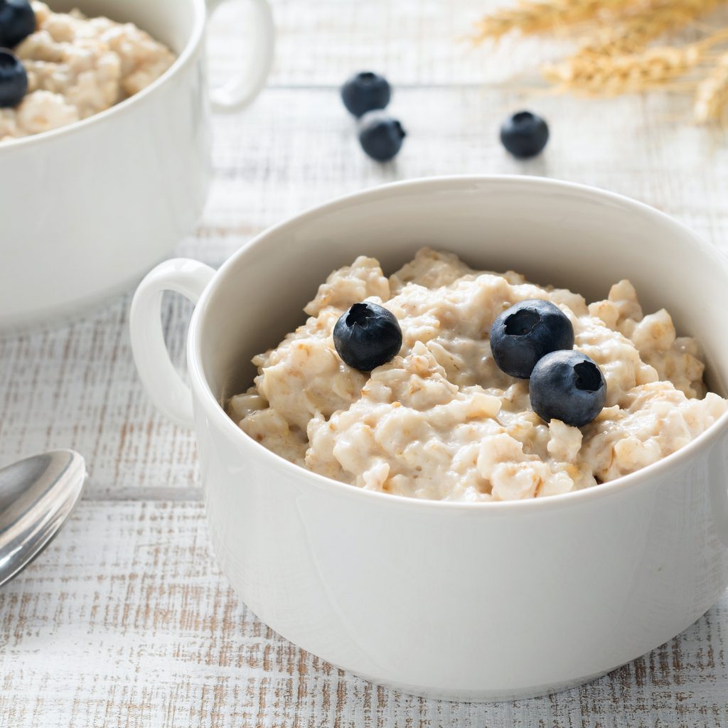 A bowl of oatmeal and blueberries sits on a breakfast table