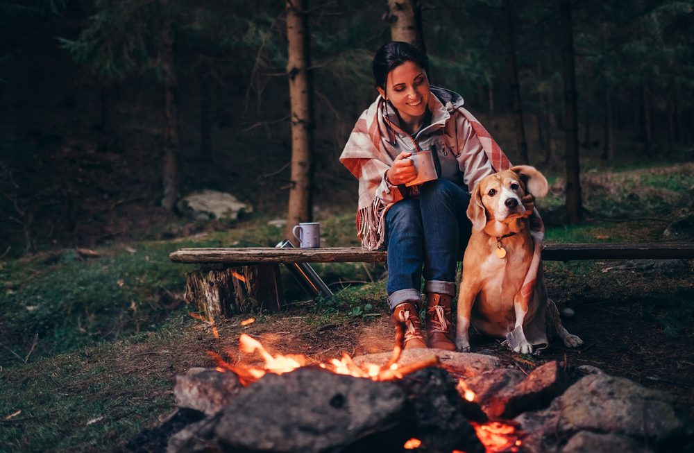 woman and dog by campfire