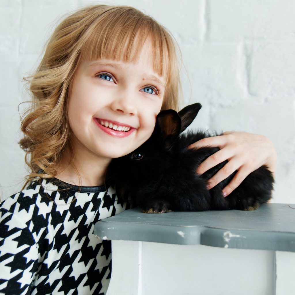 Girl hugs her pet black rabbit