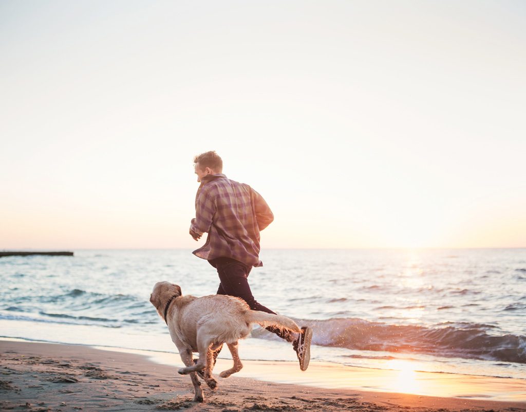 Man running on the beach with a dog. o