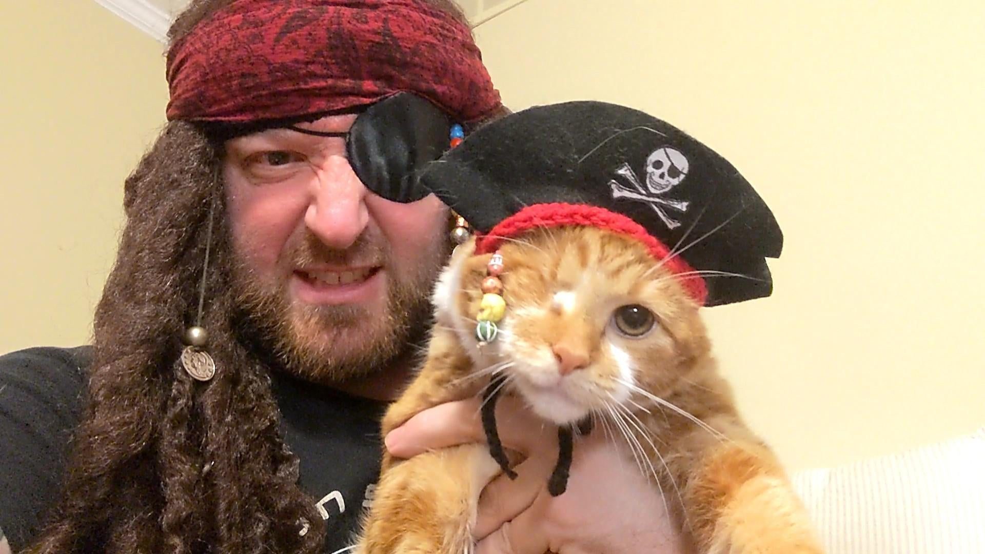 A man and his cat both dressed as Captain Jack Sparrow.
