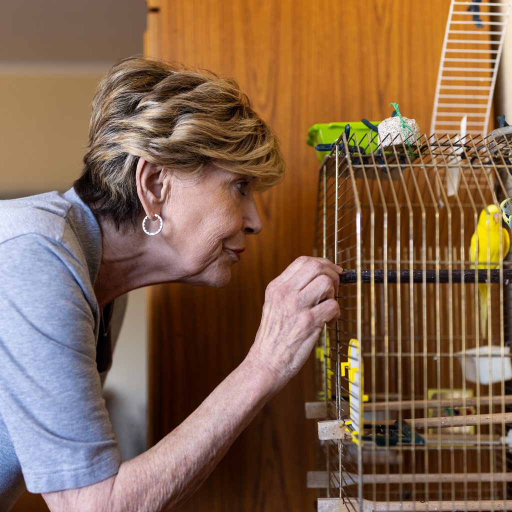 Woman feeds her birds in a cage