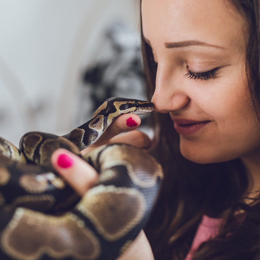Woman holds her snake up to her face