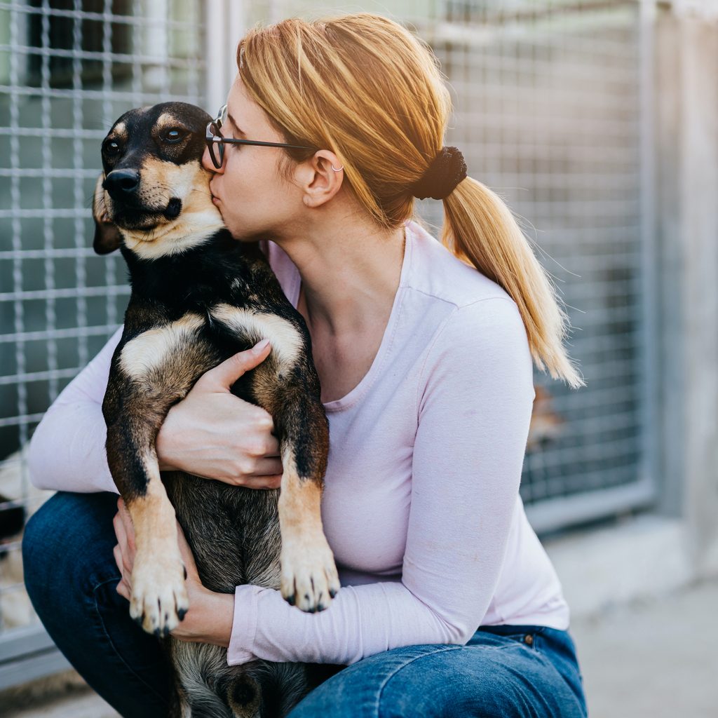 A woman hugs and kisses a dog at the shelter