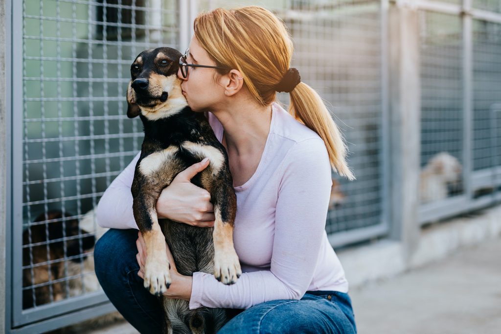 A woman hugs and kisses a dog at the shelter
