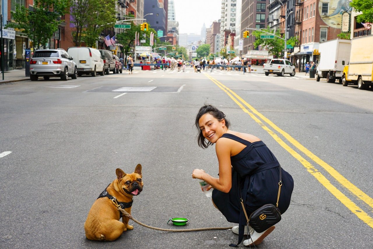 A woman exploring the city with a leashed French Bulldog.