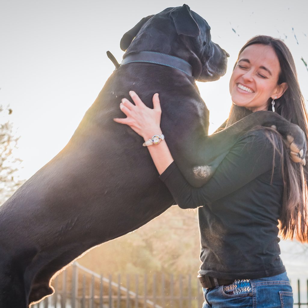 A woman hugs her Great Dane who stands with front paws on her shoulders