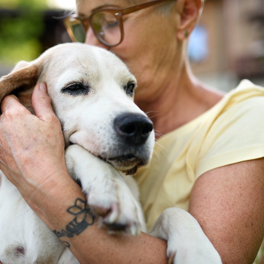 A woman hugs and kisses her senior dog