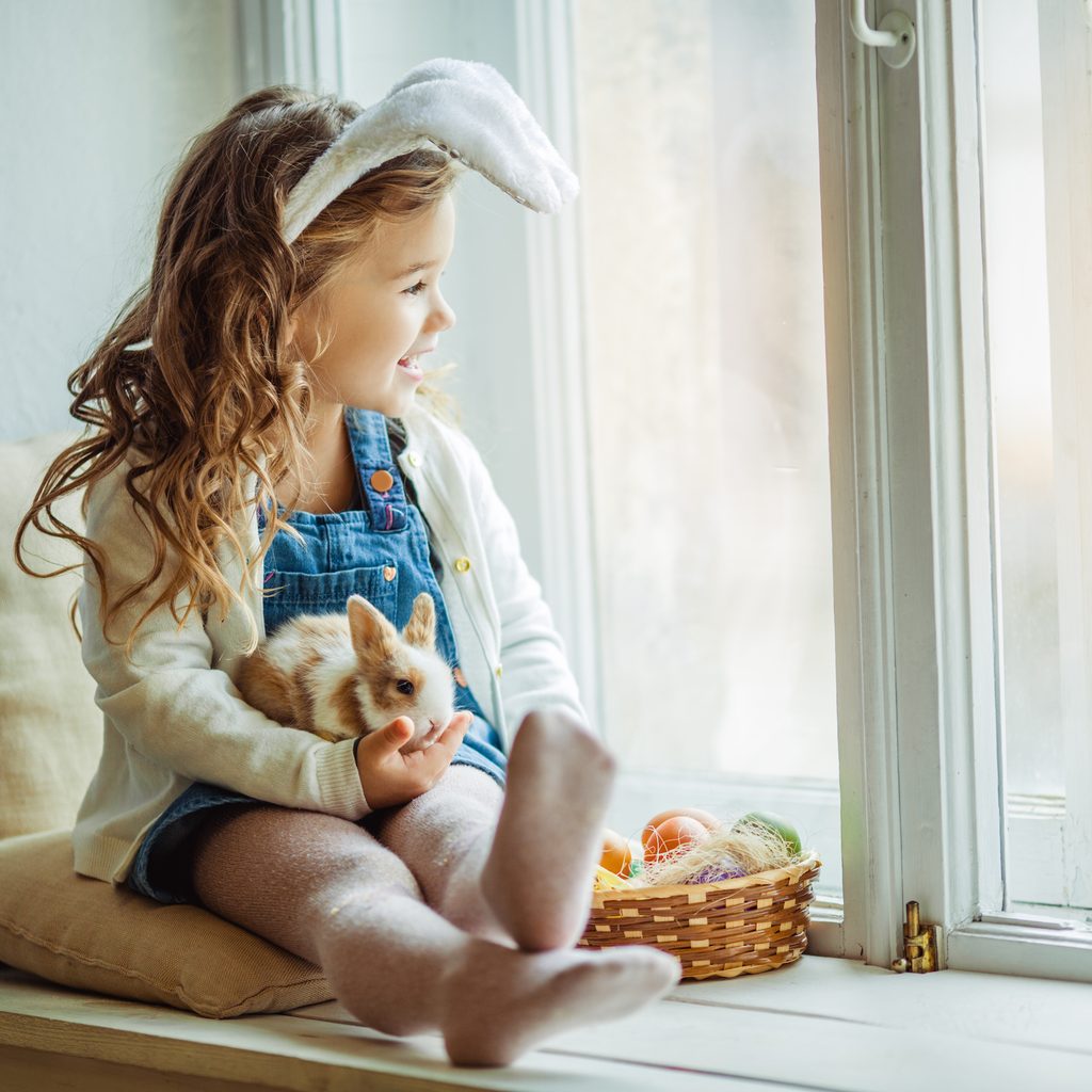 Girl with bunny ears holds her pet rabbit