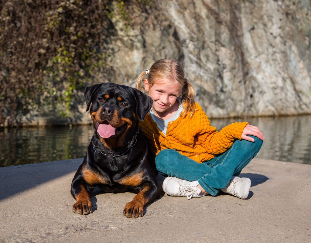 Young girl with her arm around a Rottweiler.