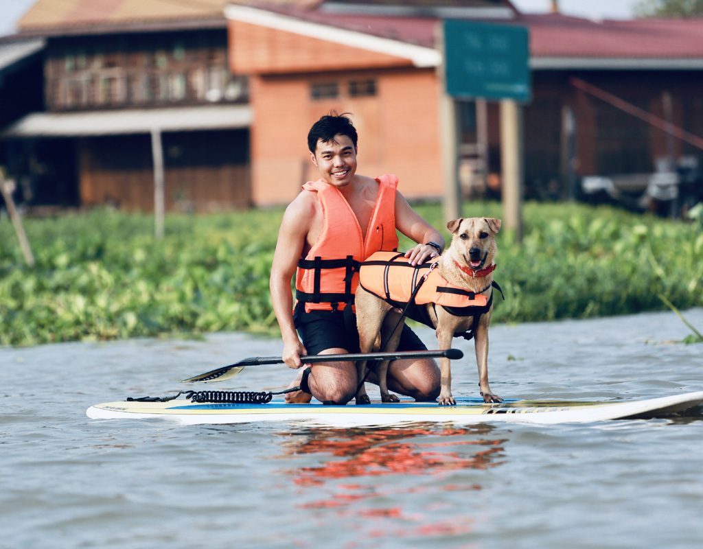 Man enjoying paddleboarding with his dog.