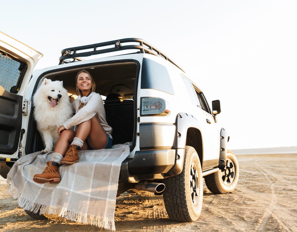 Woman sitting in the back of a car with her dog.