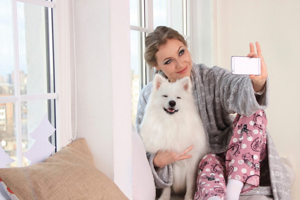 A woman taking a selfie with her white dog
