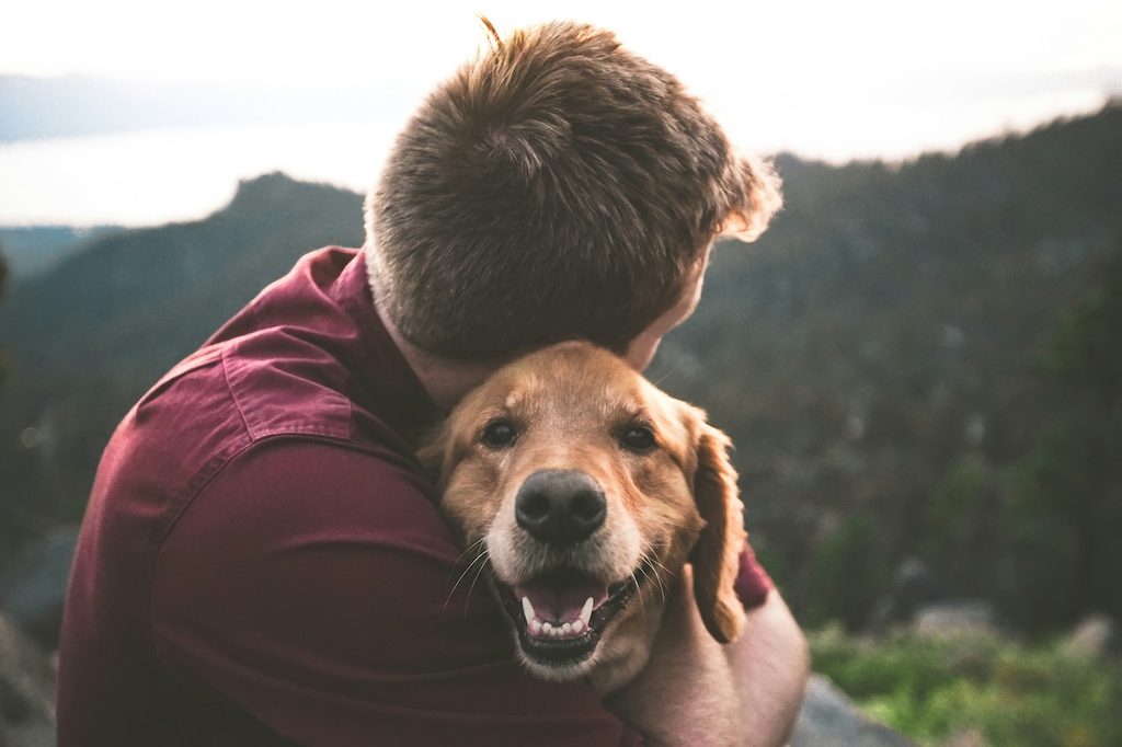 man hugging golden retriever