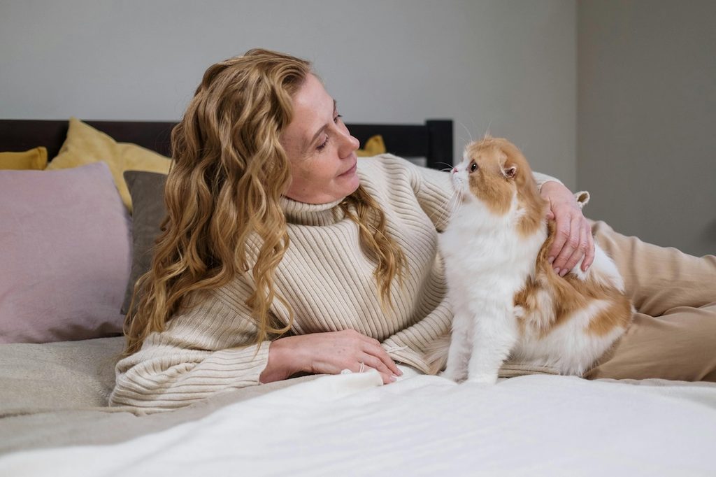 a woman and cat cuddling on bed