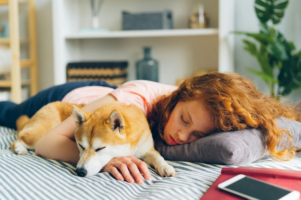 a woman with red hair sleeping with a dog and clothes on