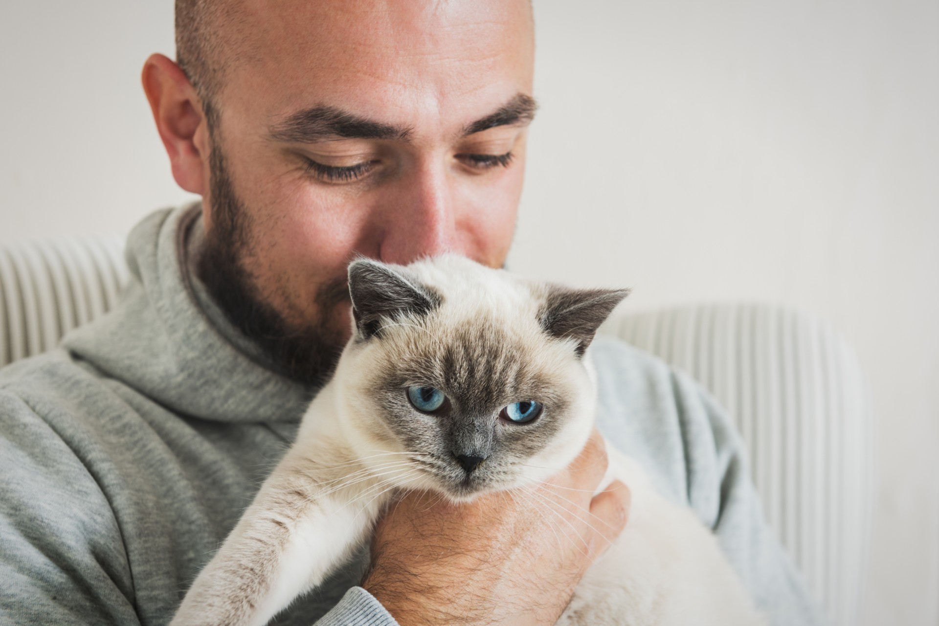 Man holding a Siamese cat
