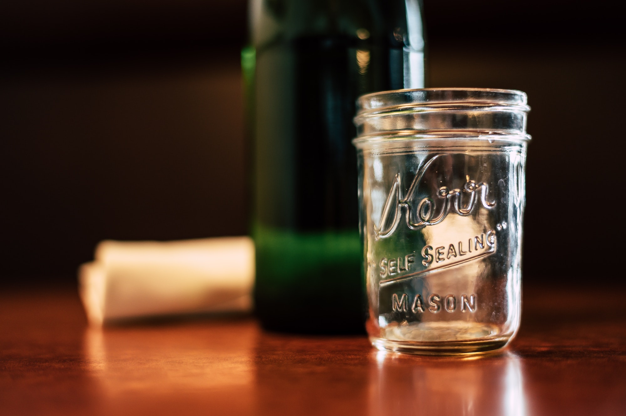 empty mason jar next to bottle and napkin