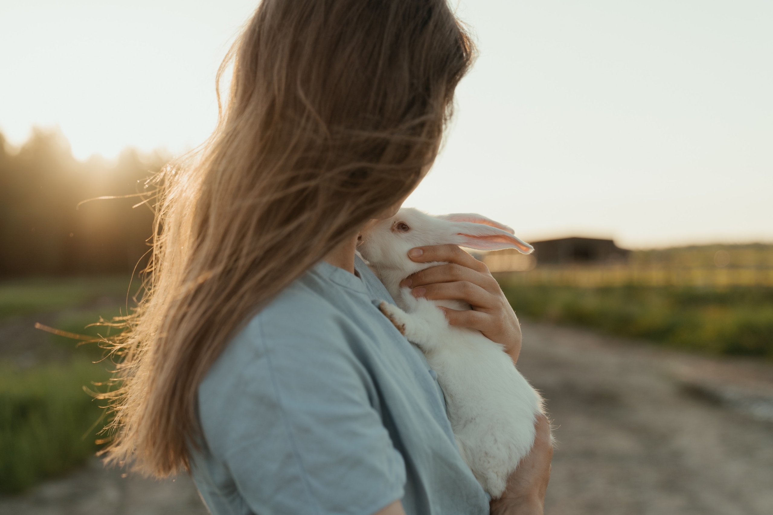 a girl with long hair holds a white rabbit to her chest