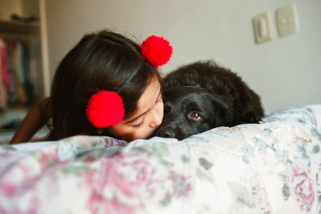 A young girl and her puppy cuddling on a bed