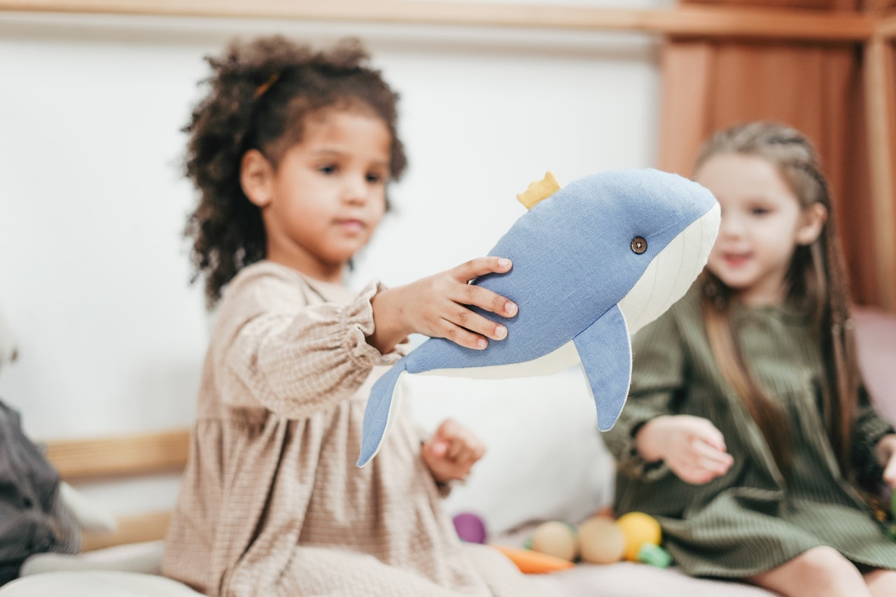 A little girl holding a stuffed blue whale.