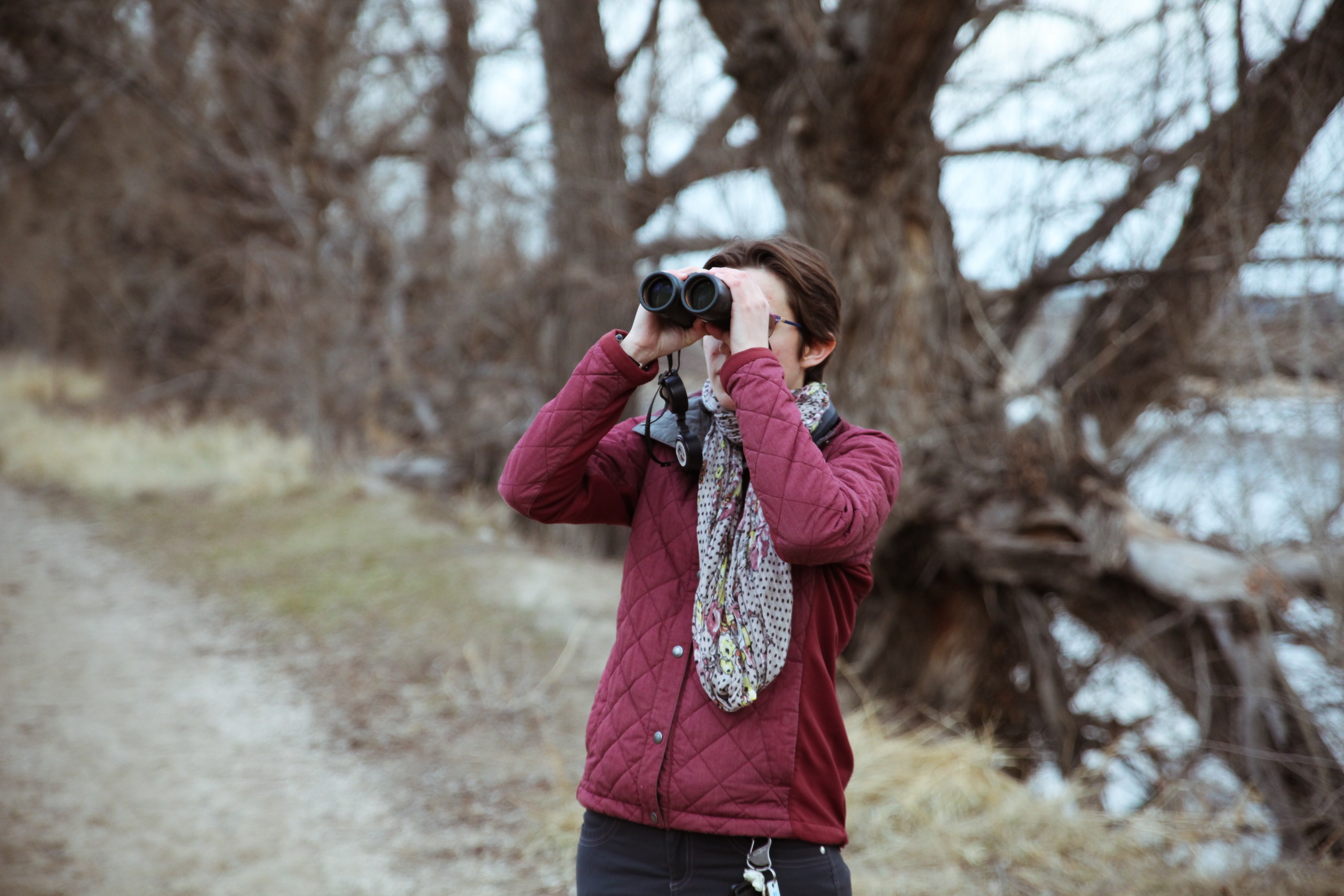 Woman looks through binoculars at a bird