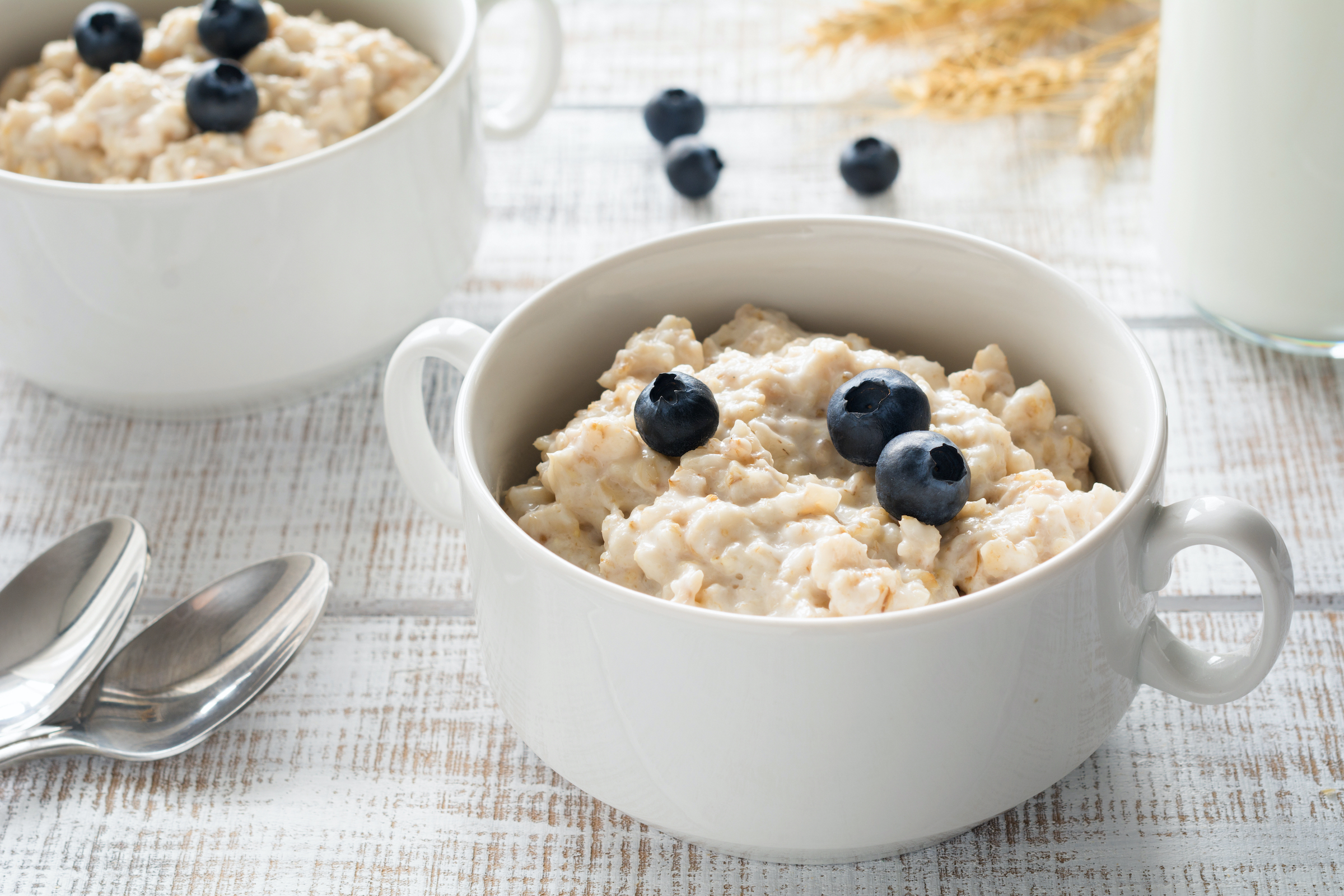 A bowl of oatmeal and blueberries sits on a breakfast table