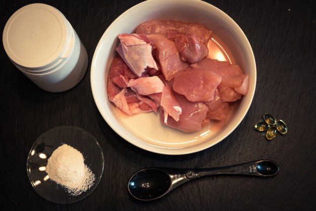A bowl of raw chicken plus supplements to feed to a pet