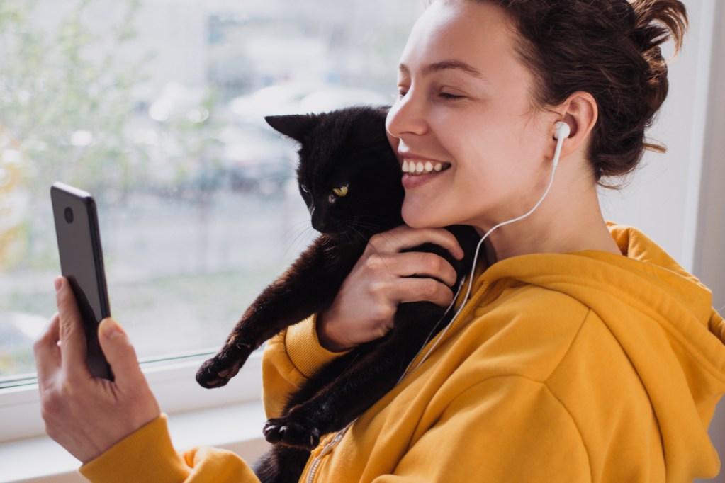 A woman takes a selfie with her black cat