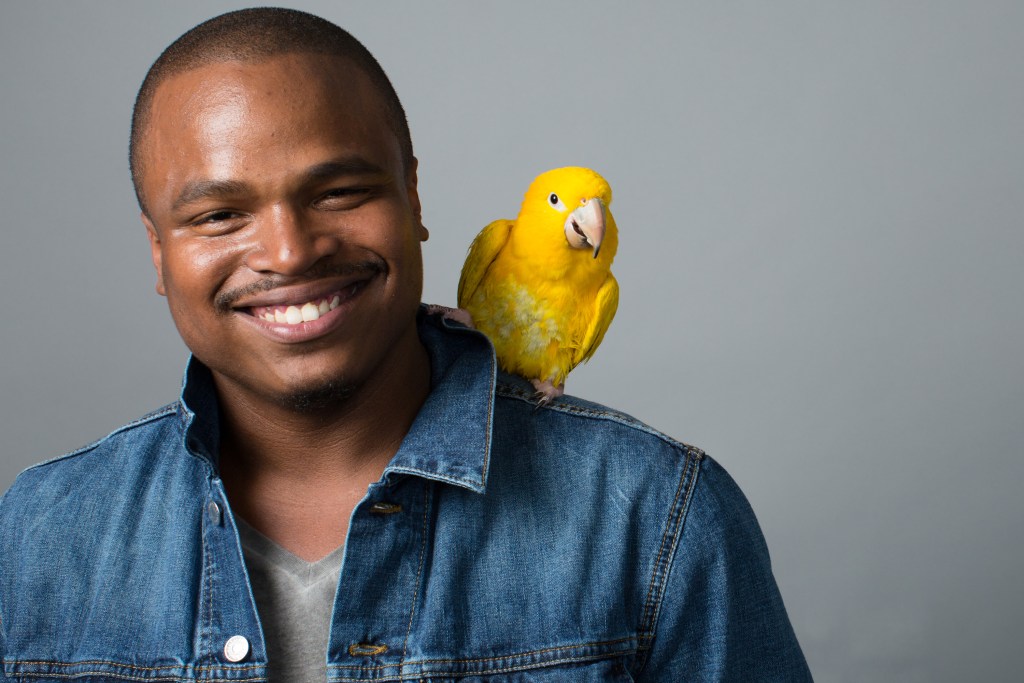 Vyras su geltonu paukščiu ant peties