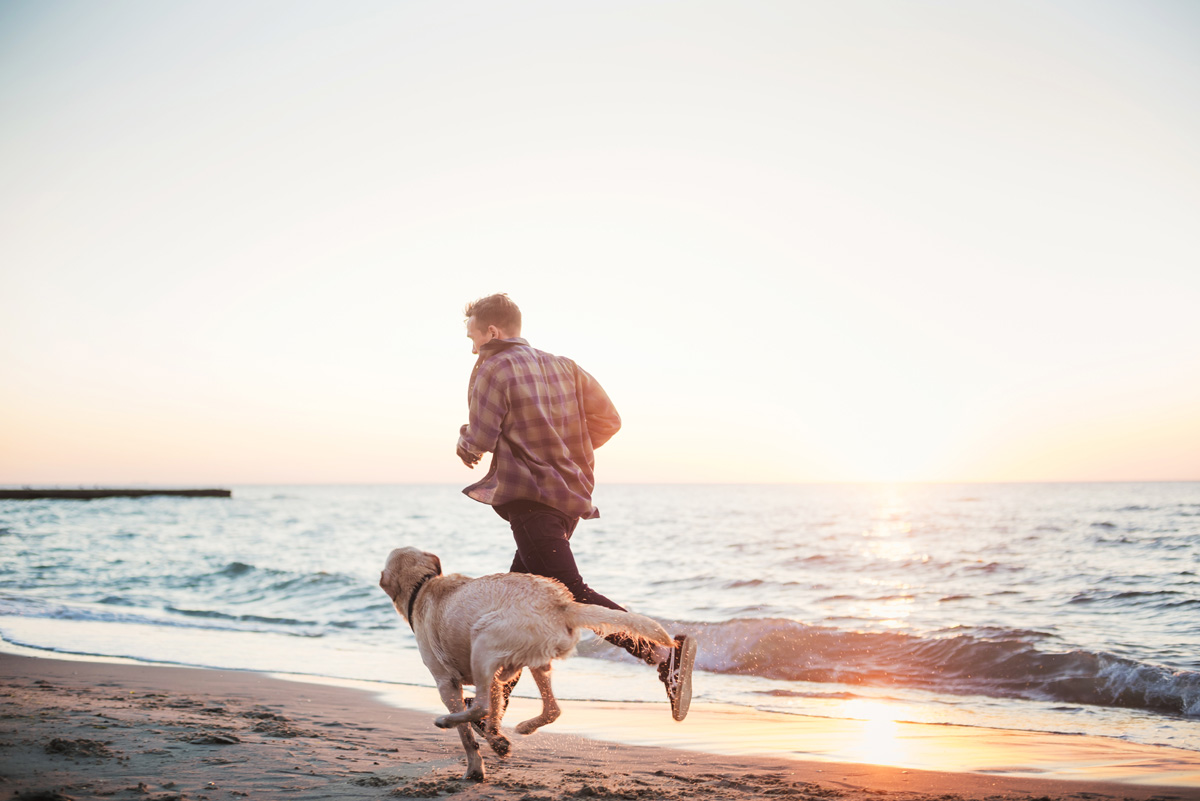 Man running on the beach with a dog. o