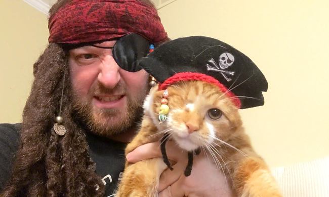 A man and his cat both dressed as Captain Jack Sparrow.