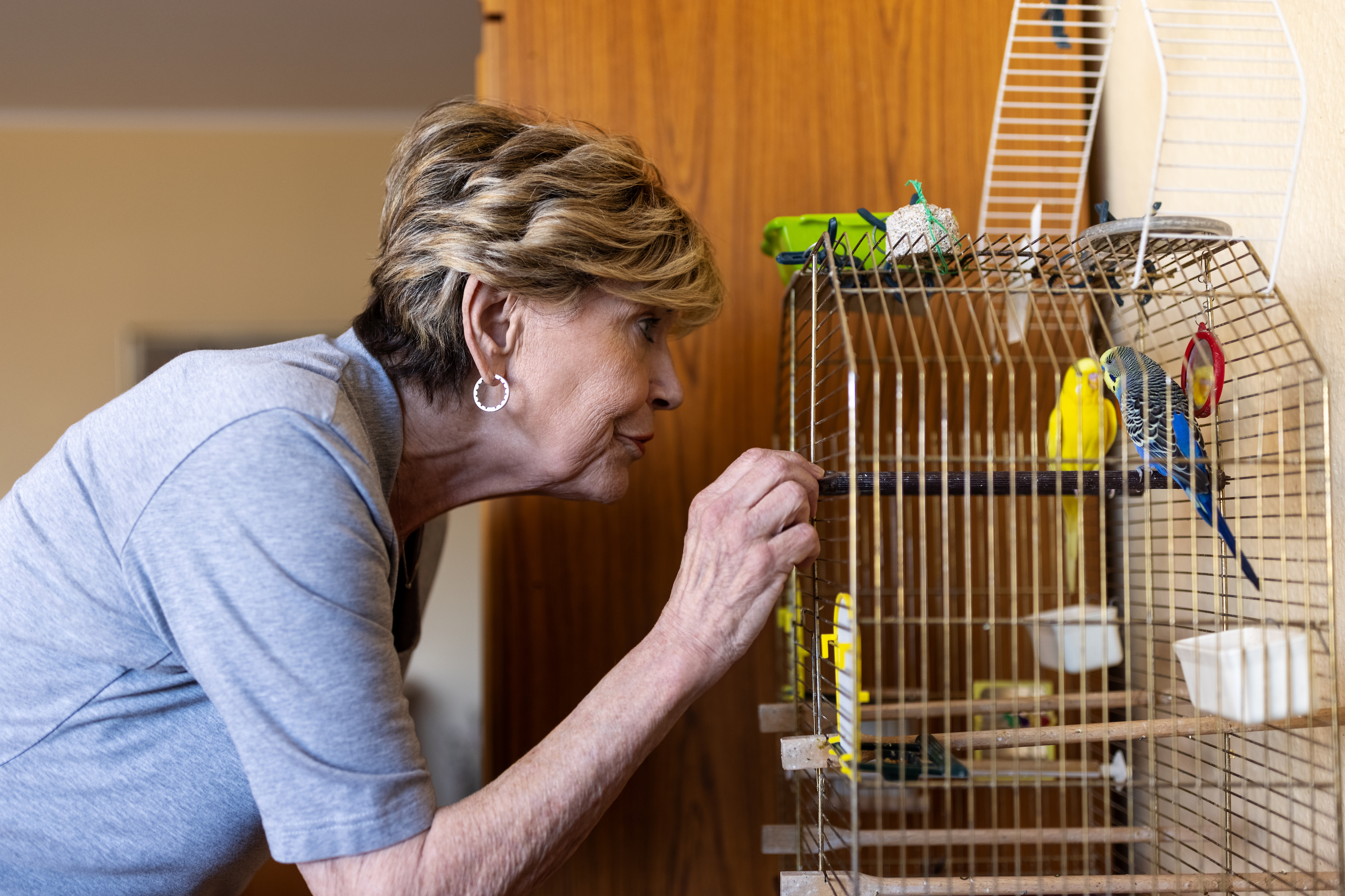 Woman feeds her birds in a cage