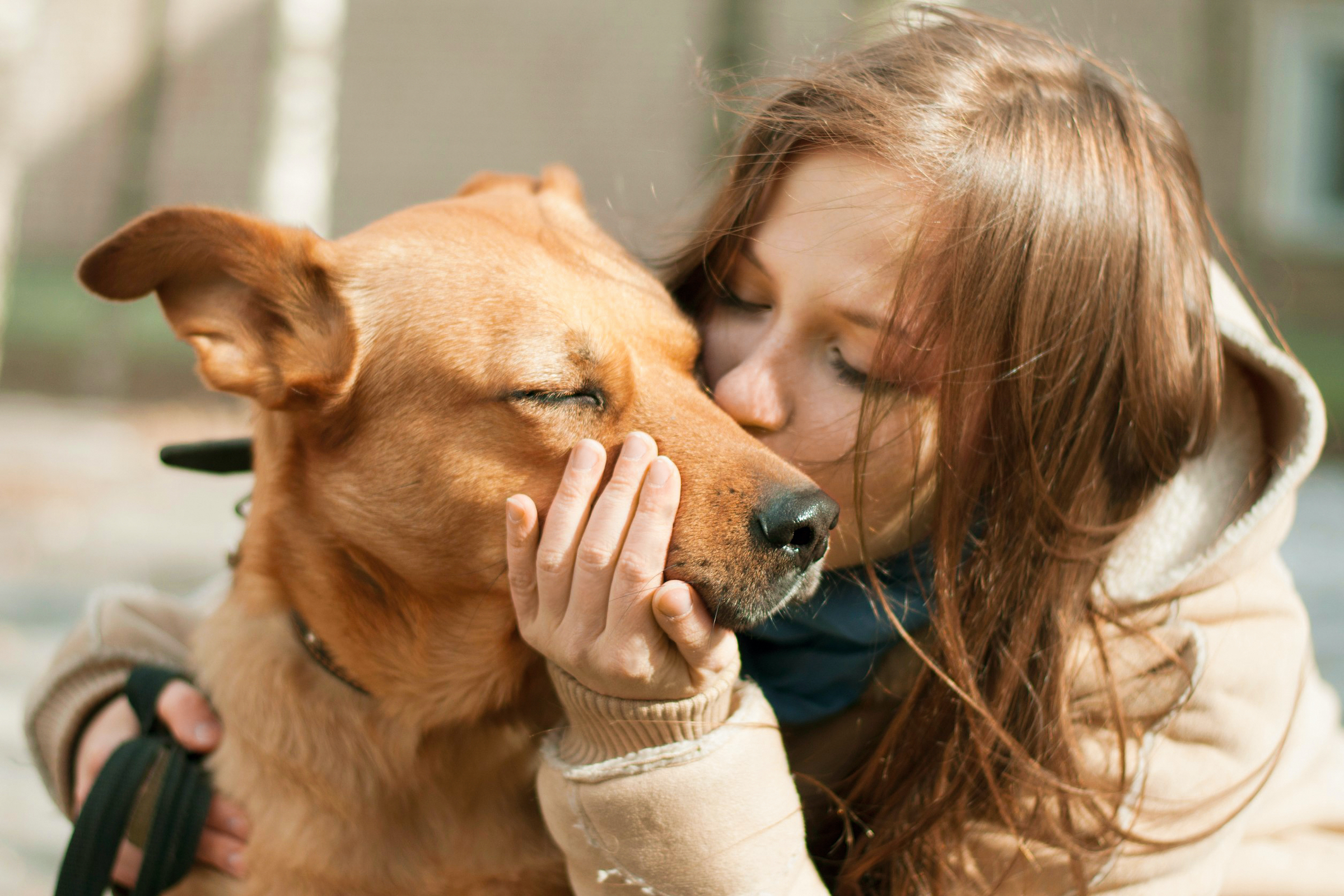 A woman holds and kisses her dog