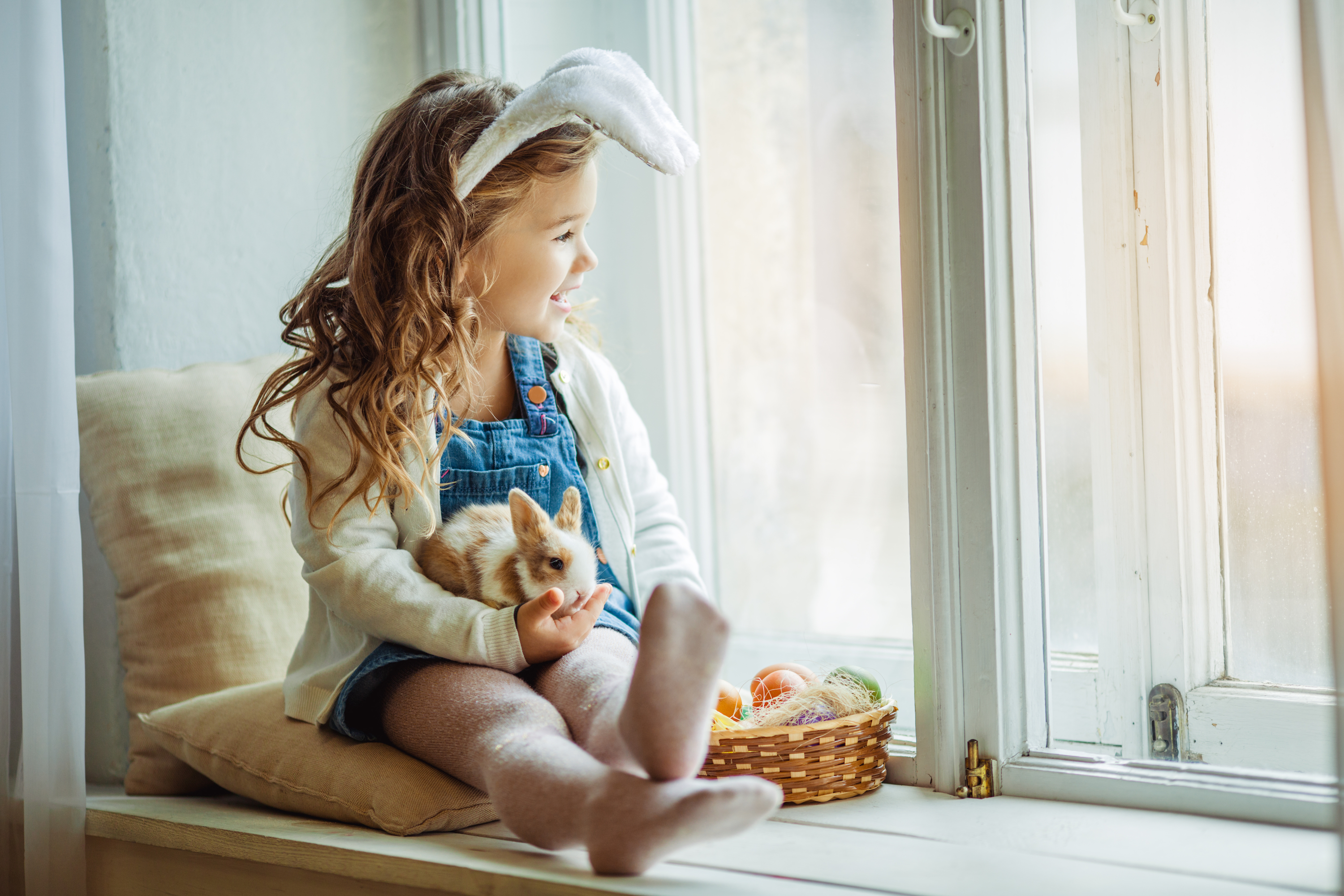 Girl with bunny ears holds her pet rabbit