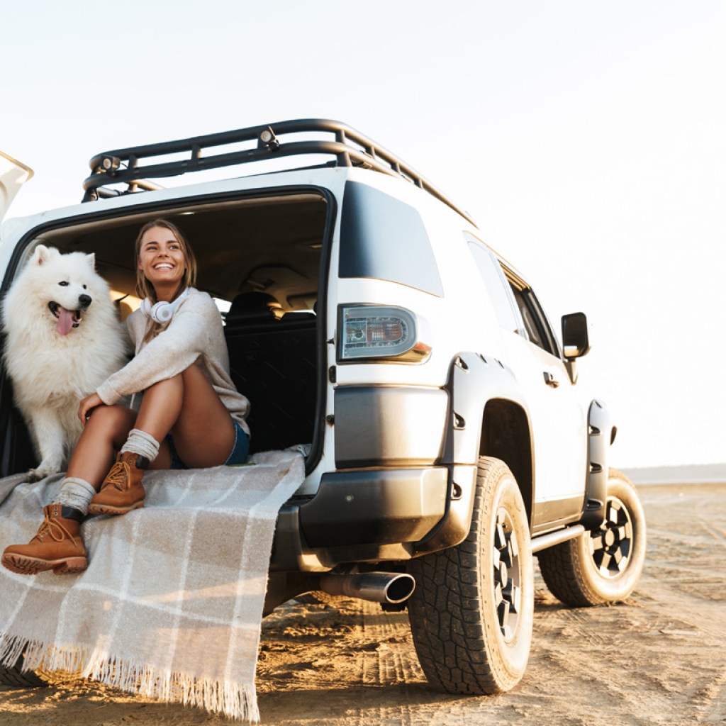 Woman sitting in the back of a car with her dog.
