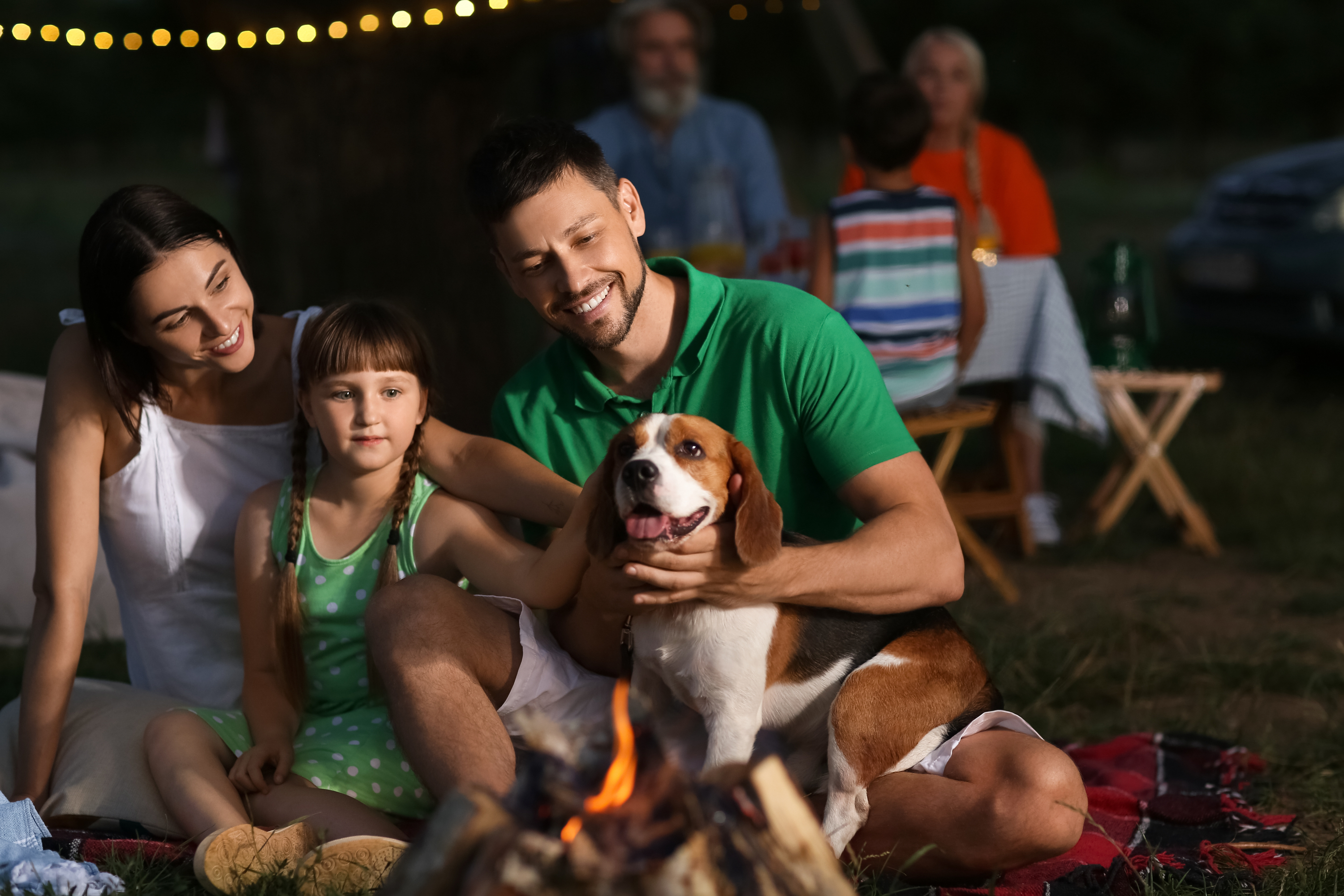 Family with their dog at night at a barbecue fire pit