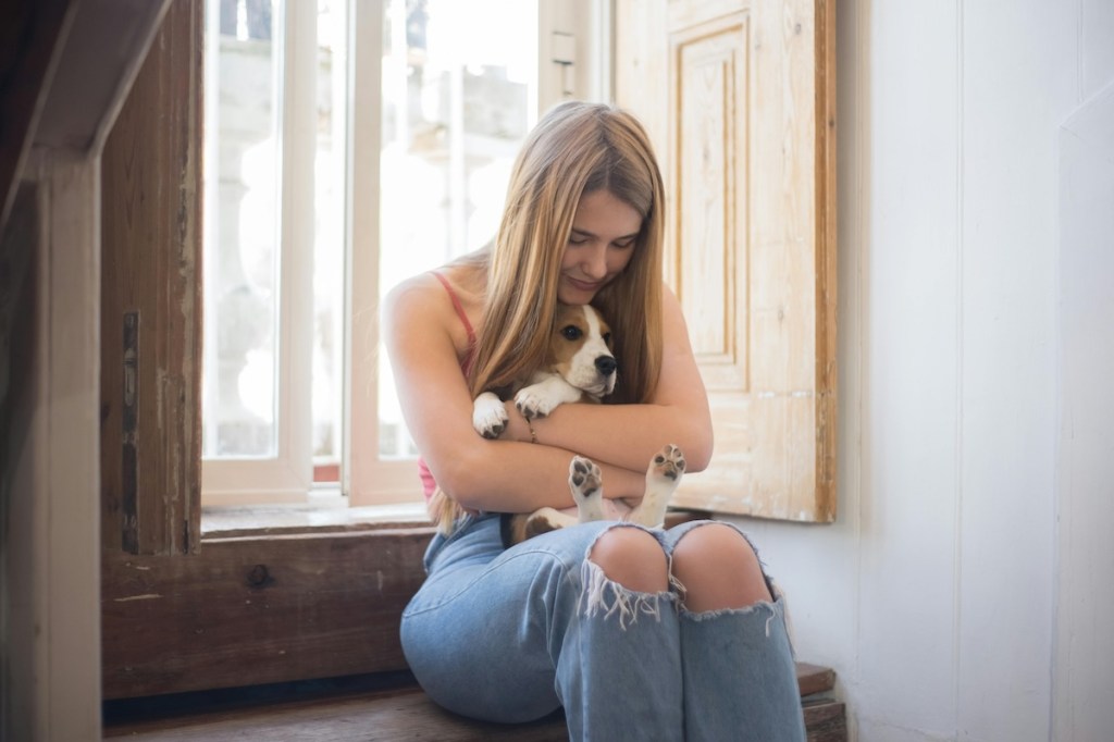 woman cuddling a hound dog